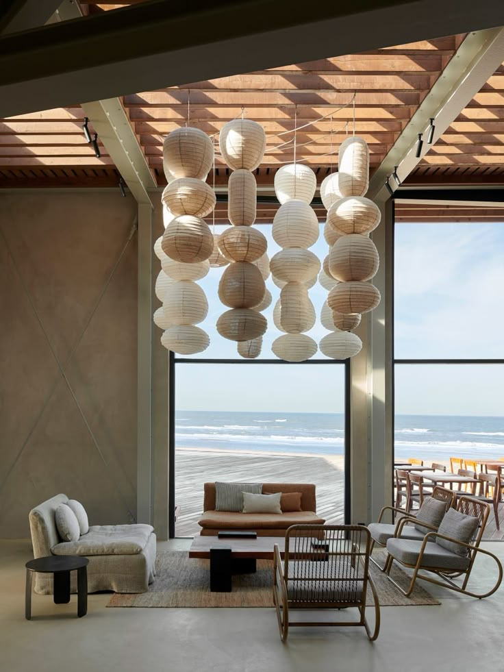 a living room filled with lots of furniture next to a large open window covered in paper lanterns