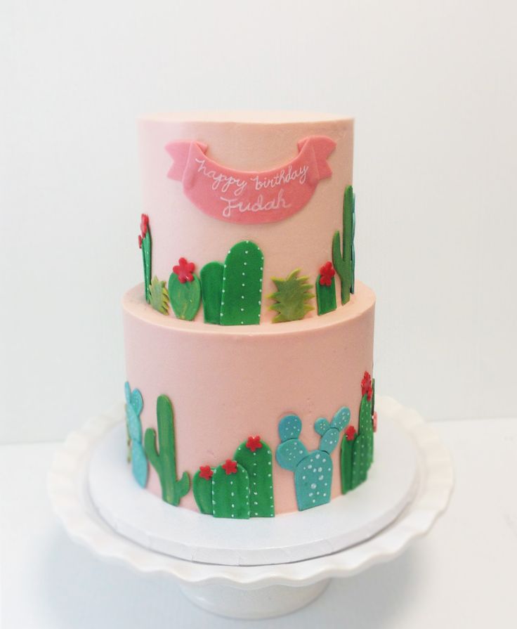 a three tiered cake decorated with cactus and pink frosting on a white plate