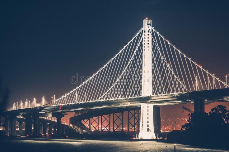 a very long bridge that is lit up in the night time with lights on it