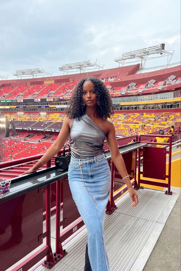 a woman standing on top of a balcony next to an empty stadium filled with red bleachers