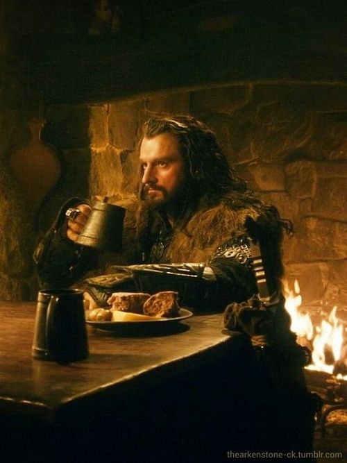 a man sitting at a table in front of a fire place drinking from a mug