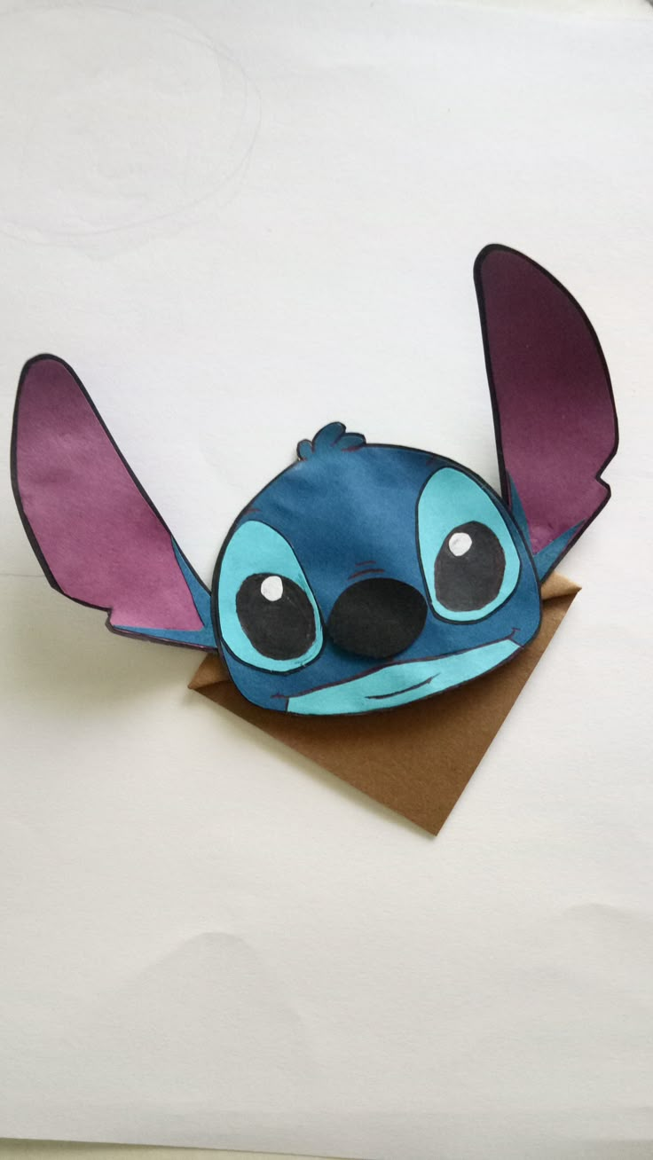 an origami stitchy bird on top of a piece of brown paper with black eyes