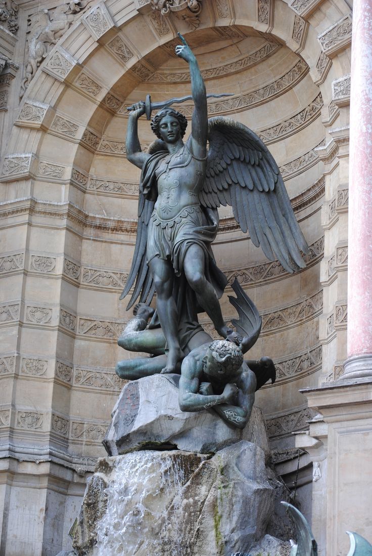 an angel statue on top of a rock in front of a stone building with arches