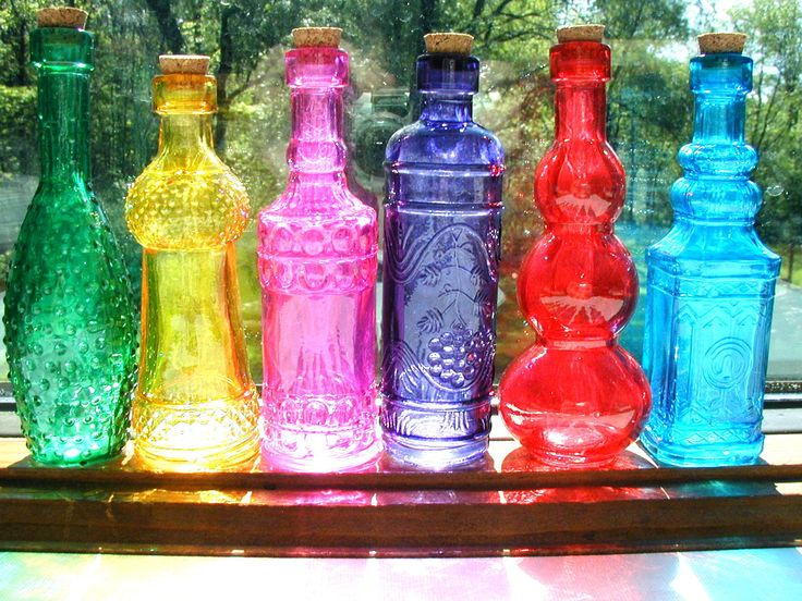 colorful glass bottles lined up on a window sill