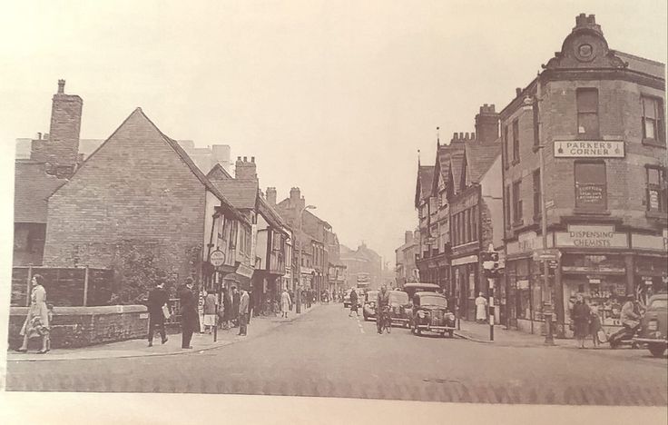 an old black and white photo of people walking down the street in front of buildings