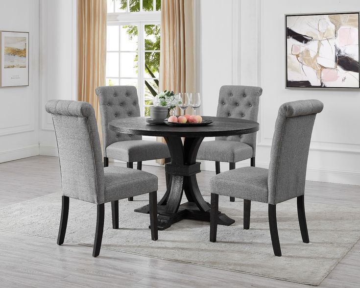 a round dining table with grey chairs and a rug on the floor in front of it