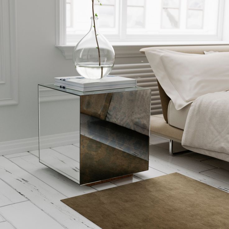 a glass table with a flower in it on a white floor next to a bed