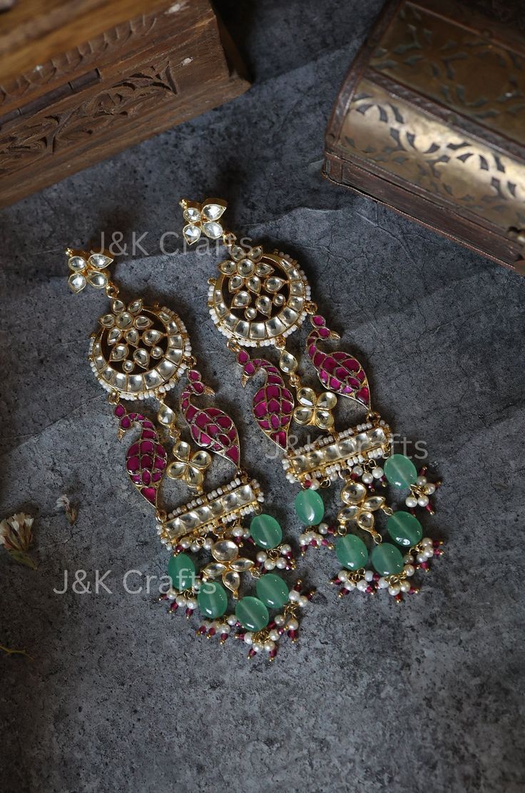 Experience the epitome of traditional elegance with our exquisite earrings, expertly encrusted with intricate Kundan details and showcasing a stunning floral design at the top. The attached peacock motifs add a touch of majestic charm, while the dangling mint Fluorite stones and trinkets of pearls create a mesmerizing display of luxury. These traditional masterpieces embody the perfect blend of classic sophistication and whimsical flair, making them ideal for special occasions or everyday opulence. Closure - Push Back  Weight - 55gm (pair) Handcrafted in Jammu and Kashmir Fusion Style Kundan Chandelier Earrings With Latkans, Fusion Style Chandelier Drop Earrings With Intricate Design, Fusion Style Kundan Earrings With Intricate Design, Fusion Style Chandbali Chandelier Earrings With Meenakari, Kundan Earrings With Intricate Design In Fusion Style, Fusion Kundan Chandelier Earrings With Latkans, Fusion Style Meenakari Drop Bridal Earrings, Festive Fusion Chandelier Earrings With Stone Work, Elegant Festive Chandelier Earrings For Ceremonial Occasions