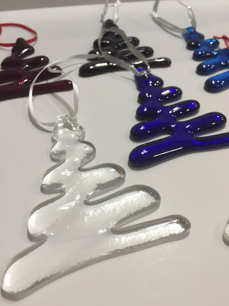 several different colored glass ornaments hanging from hooks on a white counter top with red, blue, and black beads