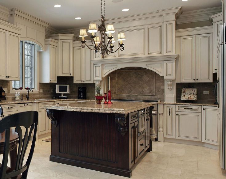 a large kitchen with an island in the middle and white cabinets on both sides, along with a chandelier hanging from the ceiling