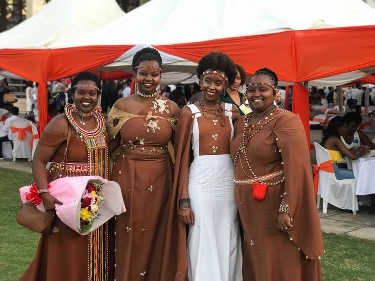 three women dressed in brown and white standing next to each other at an outdoor event