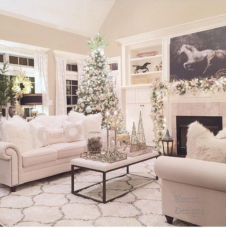 a living room decorated for christmas with white furniture and decorations on the fireplace mantel