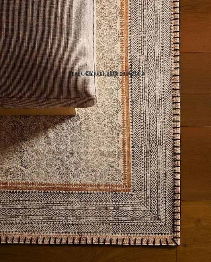 an area rug on the floor with a pillow next to it and a wooden table