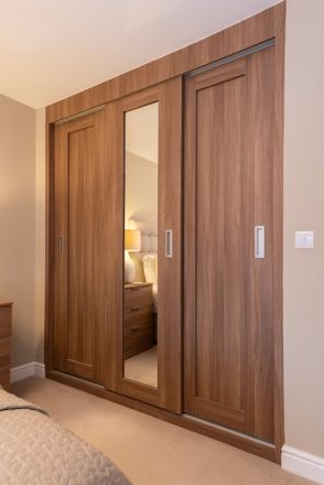 an empty bedroom with wooden closets and mirrored doors