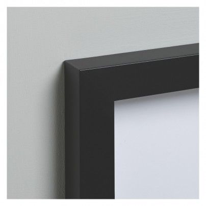 a black frame hanging on the wall next to a white wall with an empty piece of paper in it