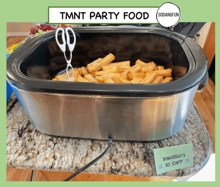 a large pot filled with french fries on top of a counter next to a sign that says tmt party food