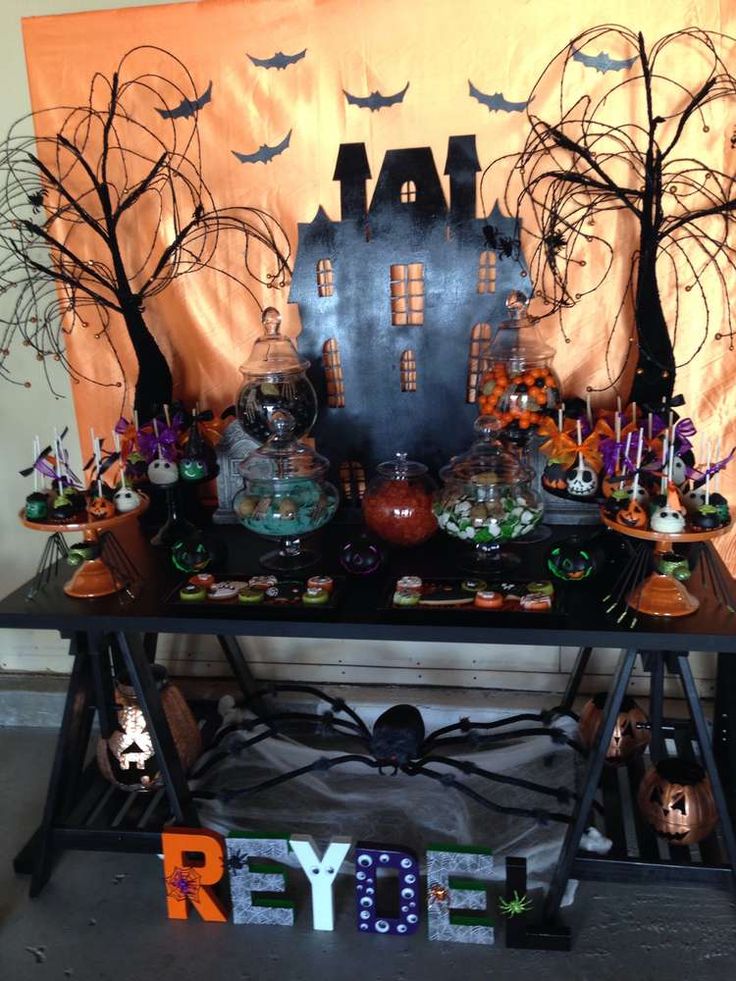 a table topped with lots of halloween decorations and candy bar top covered in spooky pumpkins