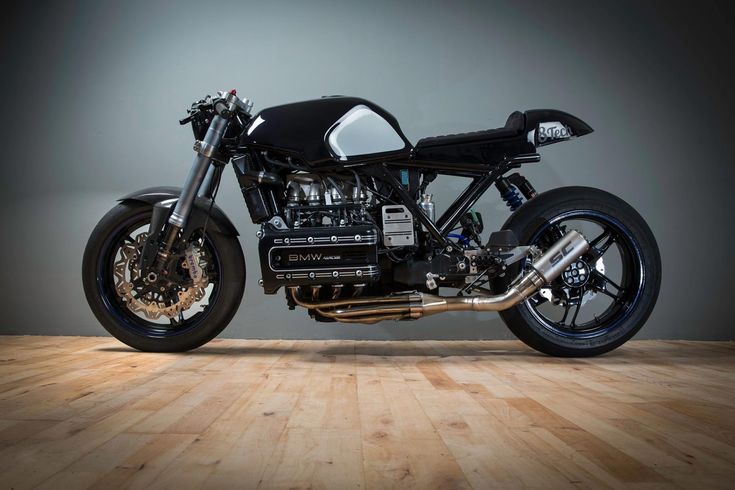 a black motorcycle parked on top of a wooden floor