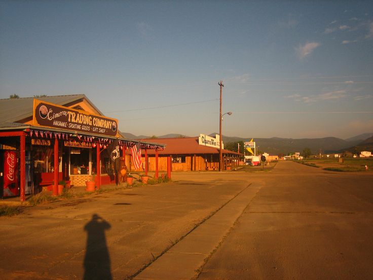 the shadow of a person standing in front of a small store on an empty street