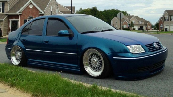 the blue car is parked on the side of the road in front of some houses