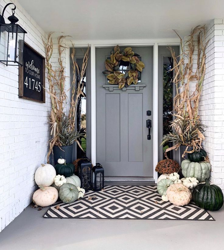 a front porch decorated for fall with pumpkins and gourds