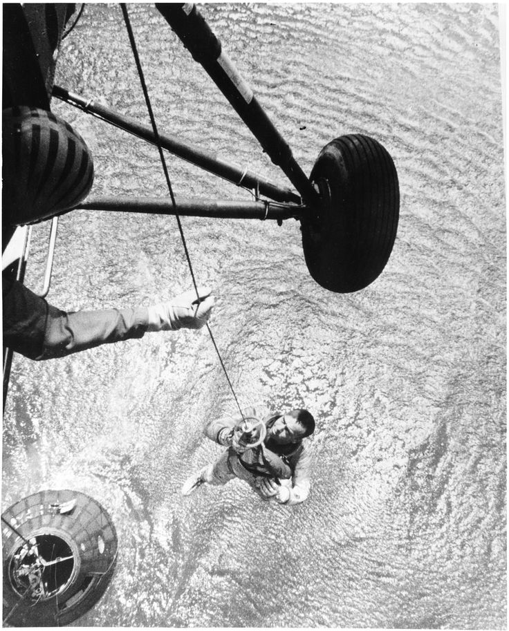 a man is in the water holding on to a rope attached to a boat's hull