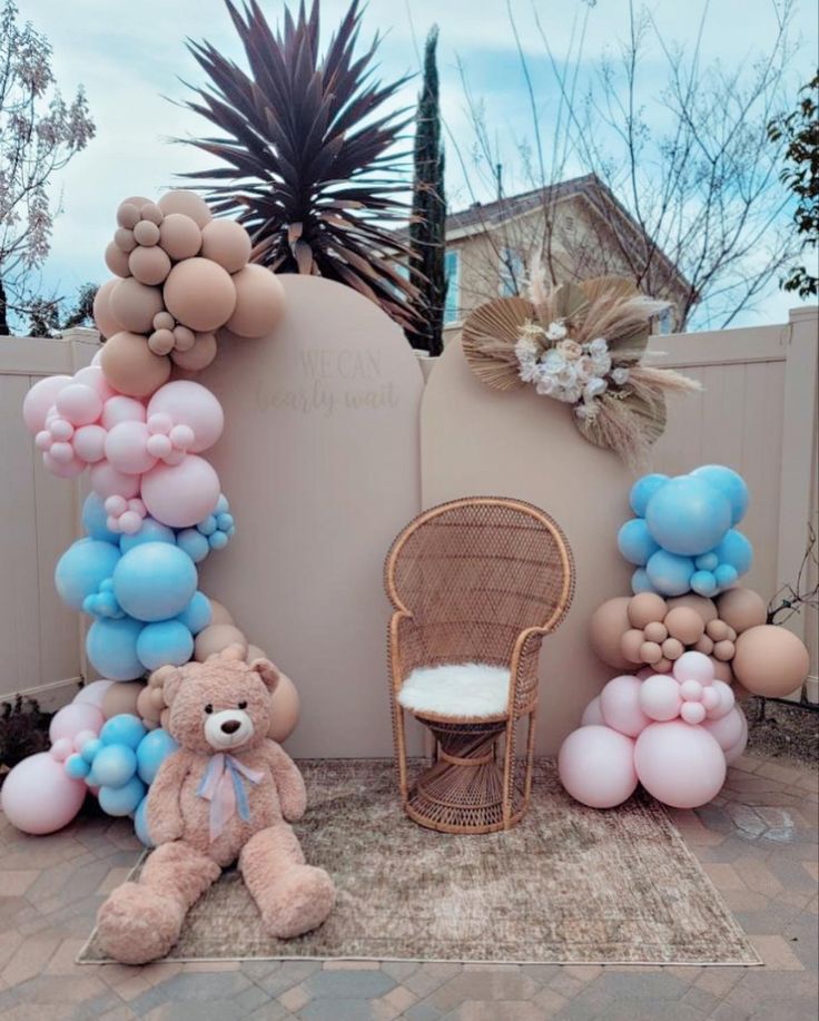 balloons and teddy bears are arranged on the ground in front of a wall with a baby's crib