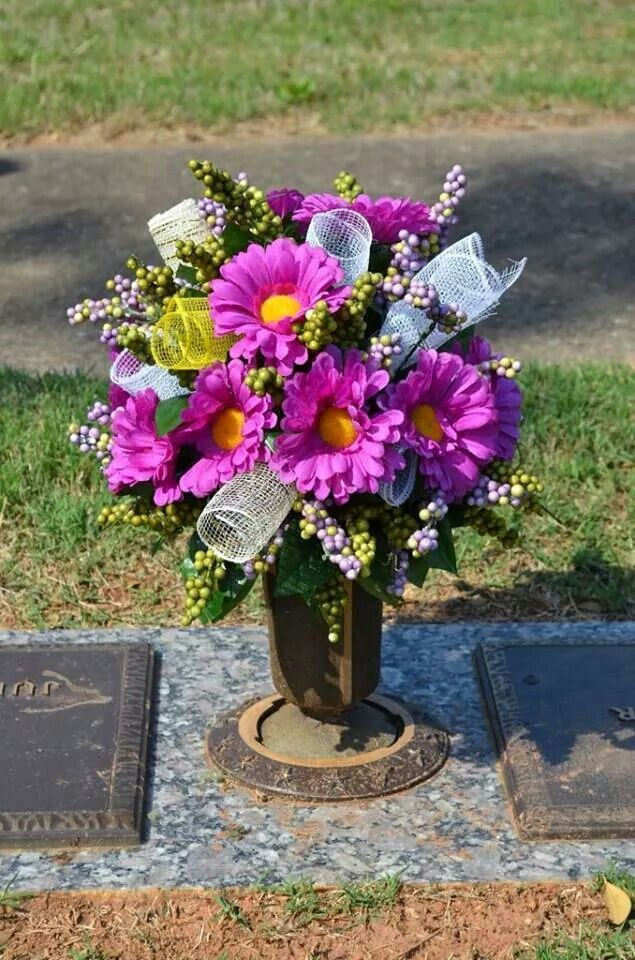 a vase filled with purple flowers sitting on top of a headstone