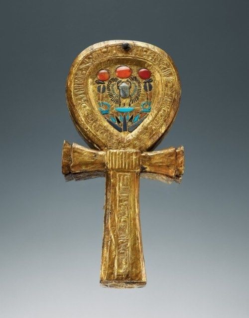 an egyptian cross is shown with gold and blue designs on the front, as well as red eyes