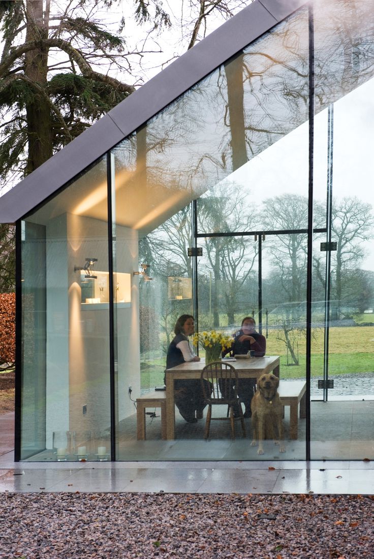 two people sitting at a table in front of a glass walled room with a dog