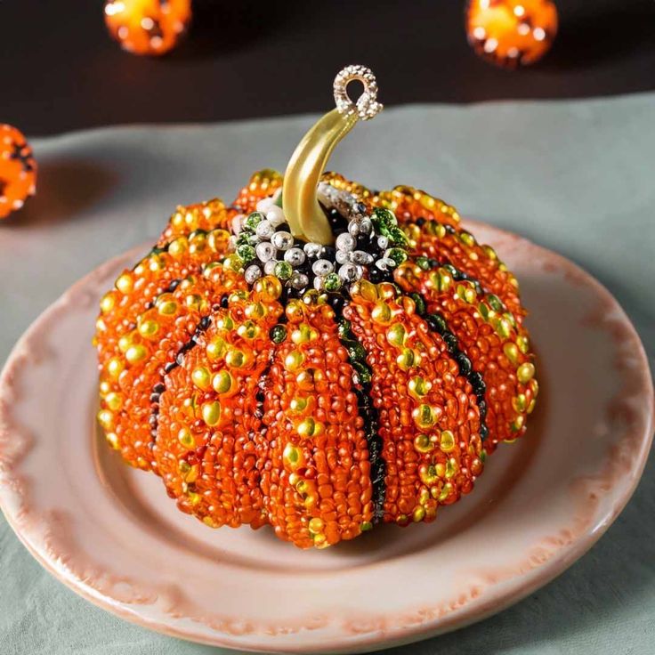 an orange beaded pumpkin sitting on top of a white plate