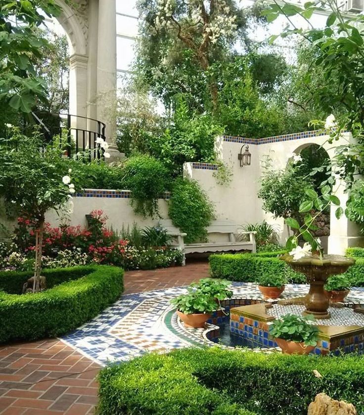 a garden with lots of plants and flowers on it's sides, surrounded by trees