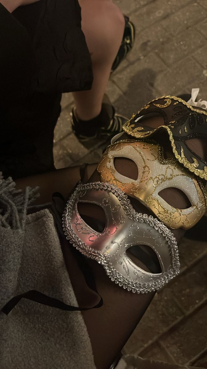 two masquerade masks sitting next to each other on a table in front of a woman