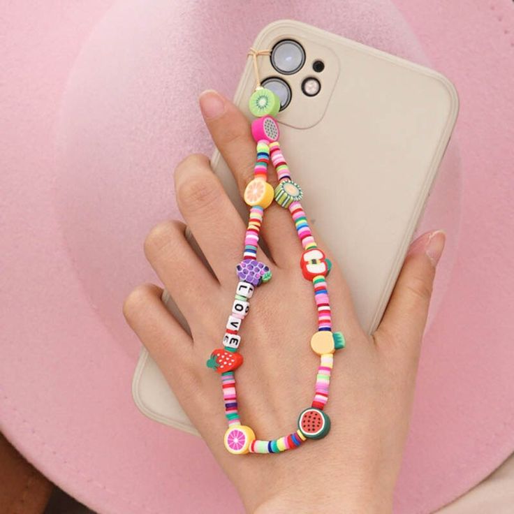 a person holding a cell phone with colorful beaded bracelets on their wrist and hand