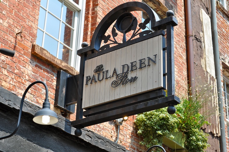 a restaurant sign hanging from the side of a brick building next to a lamp post