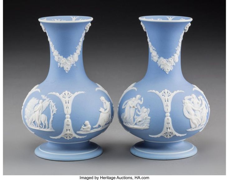 two blue and white vases sitting side by side on a gray surface with an image of people