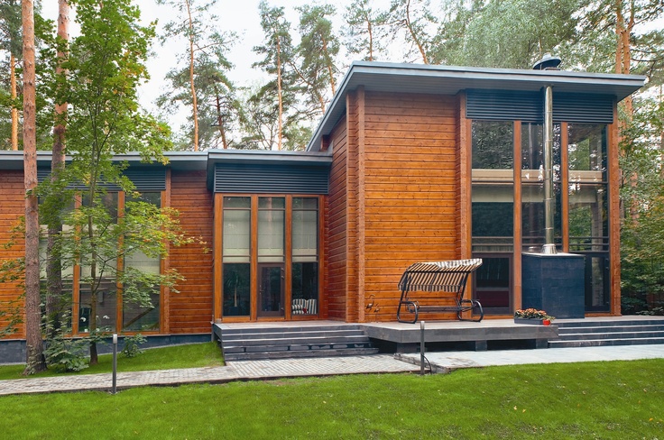 a wooden house in the woods with stairs leading up to it's front door