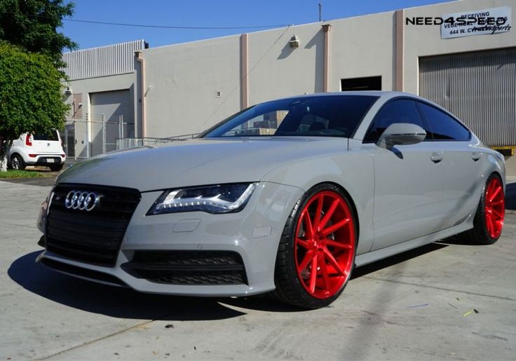 a white car with red rims parked in front of a building