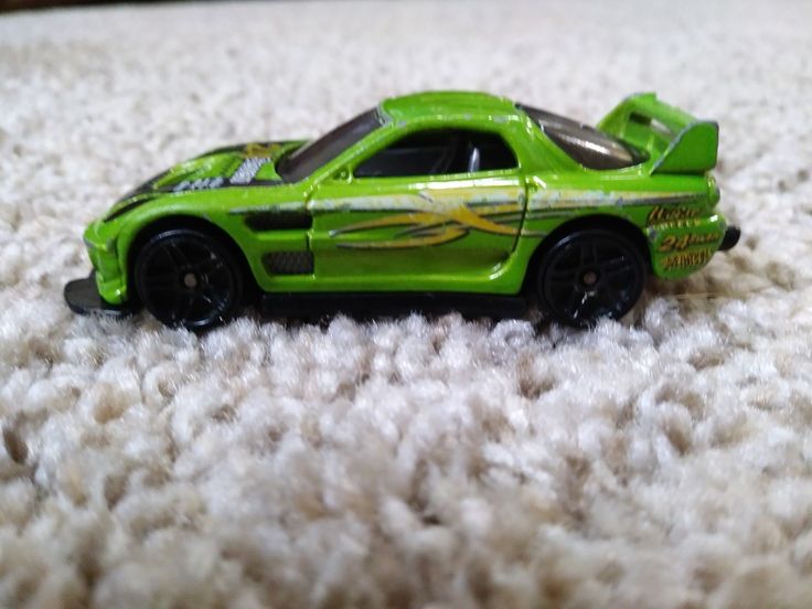 a green toy car sitting on top of a white carpet