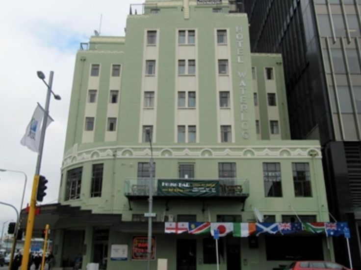 a large green building with flags on the front and side walk up to it's entrance