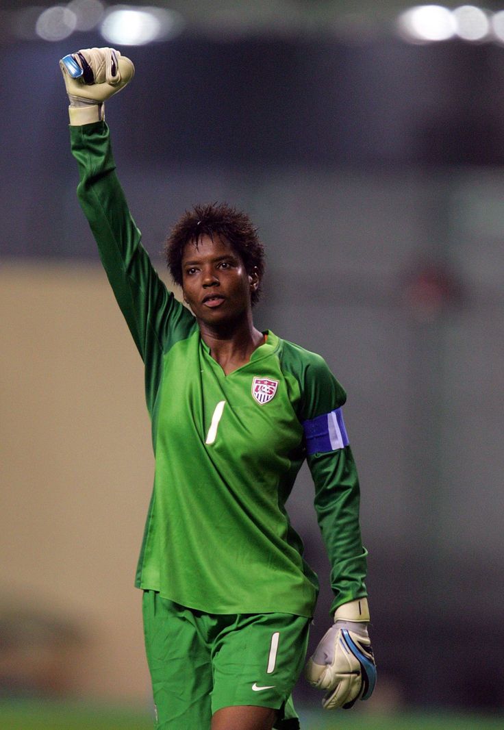 a soccer player is holding his hands up in the air while wearing green and white