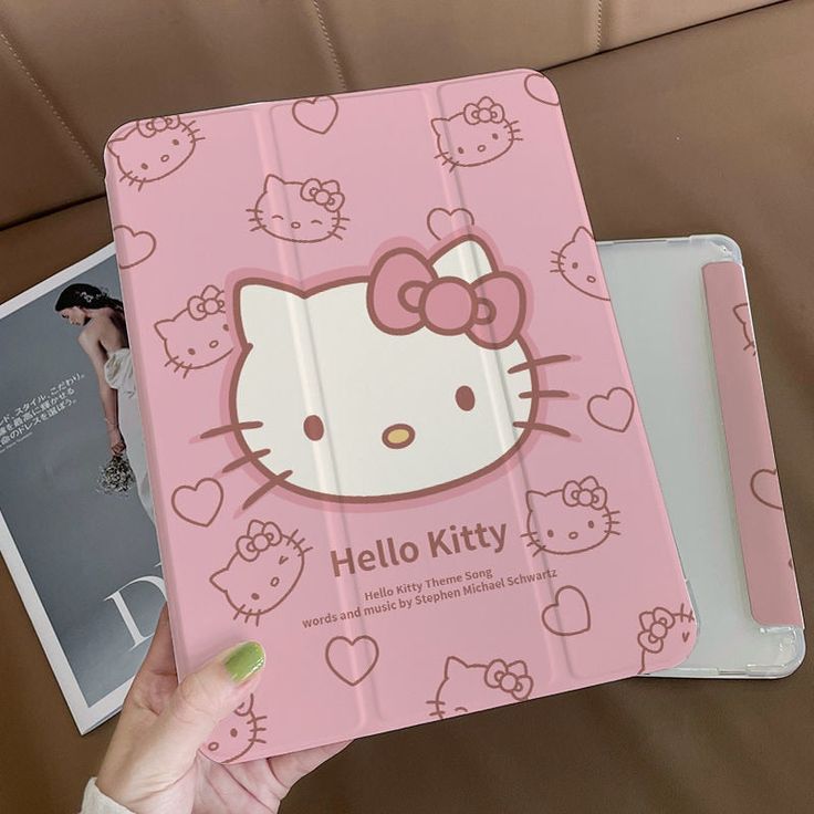 the hello kitty book is being held up by a woman's hand on a couch