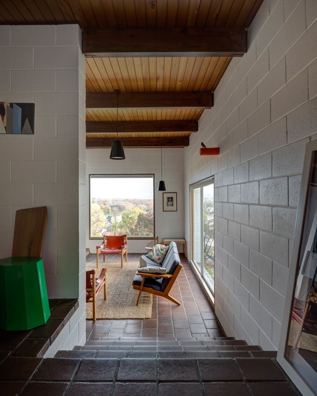 a living room filled with furniture next to a wall covered in wood planks and windows