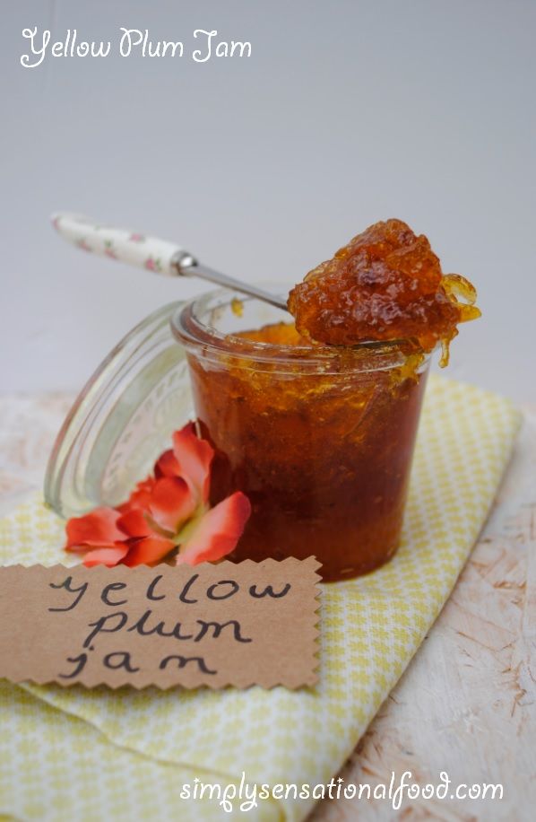 a jar filled with jam sitting on top of a yellow towel next to a flower