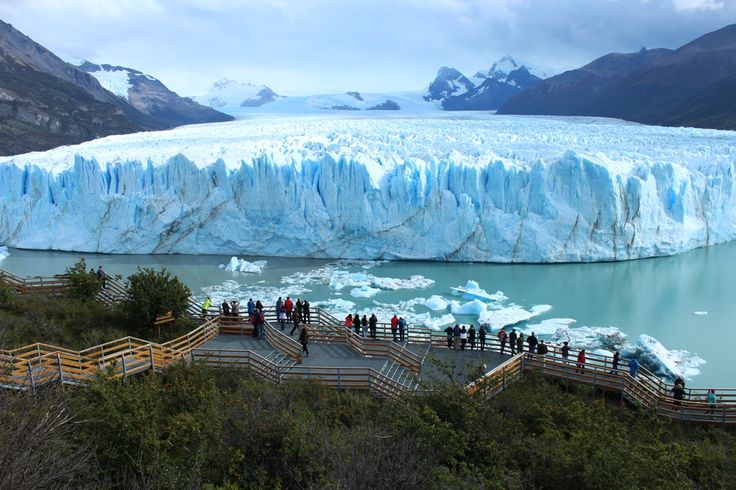 many people are standing on the steps leading to an ice - covered mountain and glacier