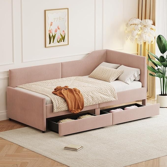 a pink daybed with drawers underneath it in a white room next to a potted plant