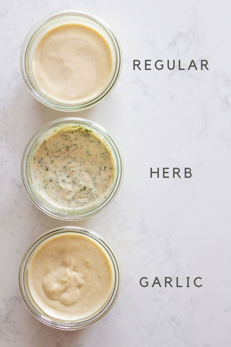 three jars filled with different types of sauces on top of a white countertop