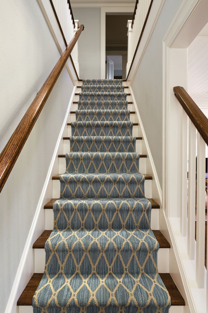 blue carpeted stairs leading up to the second floor in a home with white walls