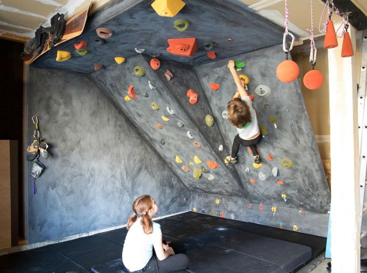 two children are climbing on an indoor climbing wall