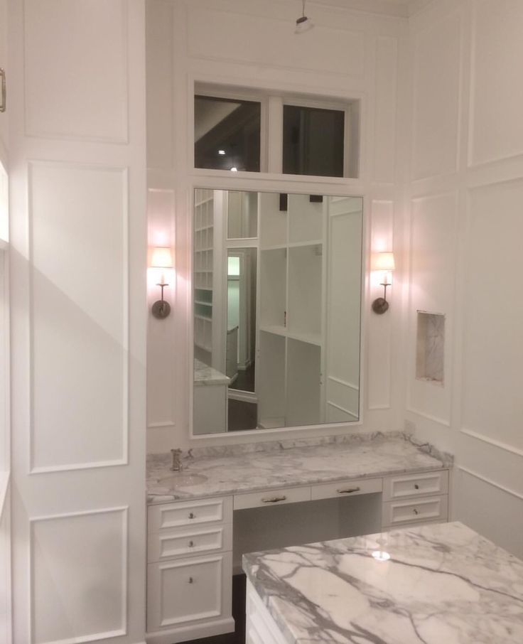 an image of a bathroom setting with marble counter tops and white cabinets on the walls